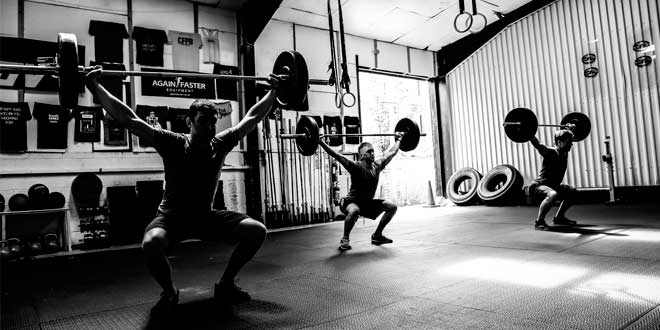 Three people doing squats at the gym