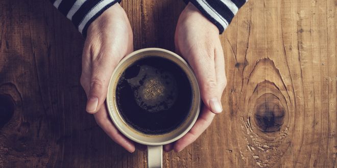 A person holding a cup of coffee A person holding a cup of coffee