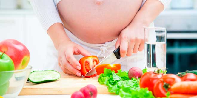 Pregnant woman cutting some veggies
