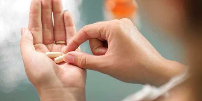Woman with two capsules in her hand