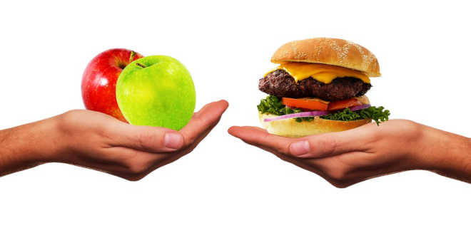 Hand holding two apples and hand holding a hamburguer