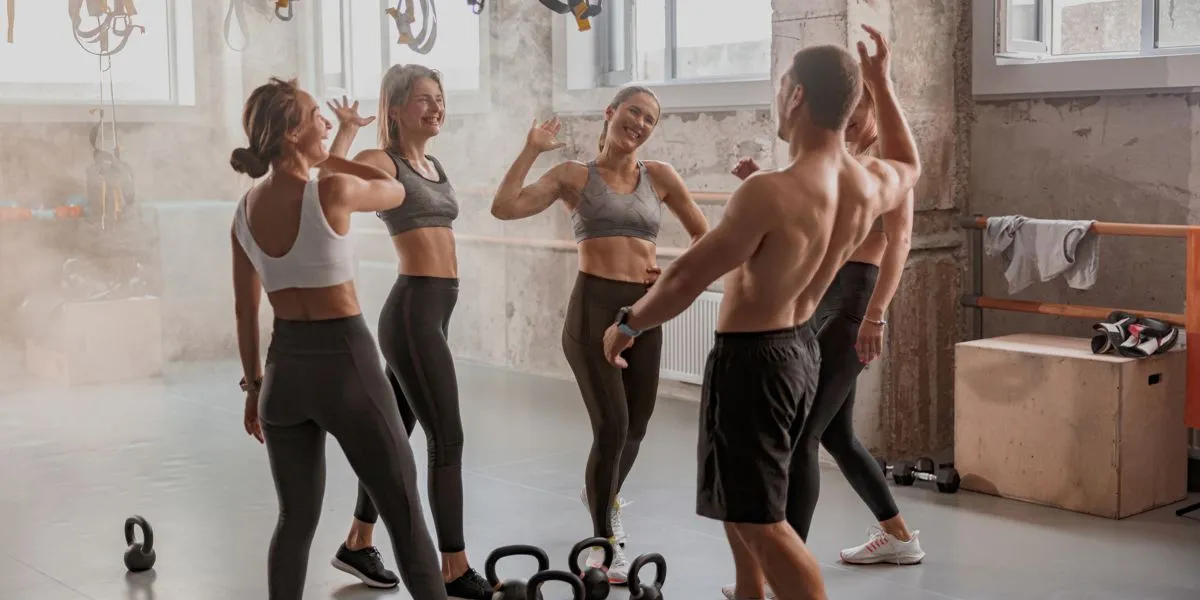 Training group in a gym finishing a session and high-fiving cheerfully