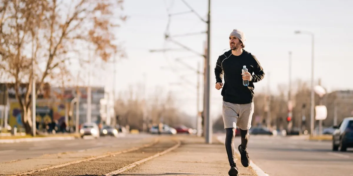 Runner holding a water bottle wearing a cap Runner holding a water bottle wearing a cap