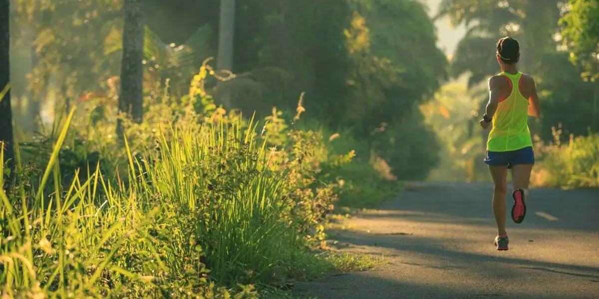 Female runner on asphalt next to vegetation Female runner on asphalt next to vegetation